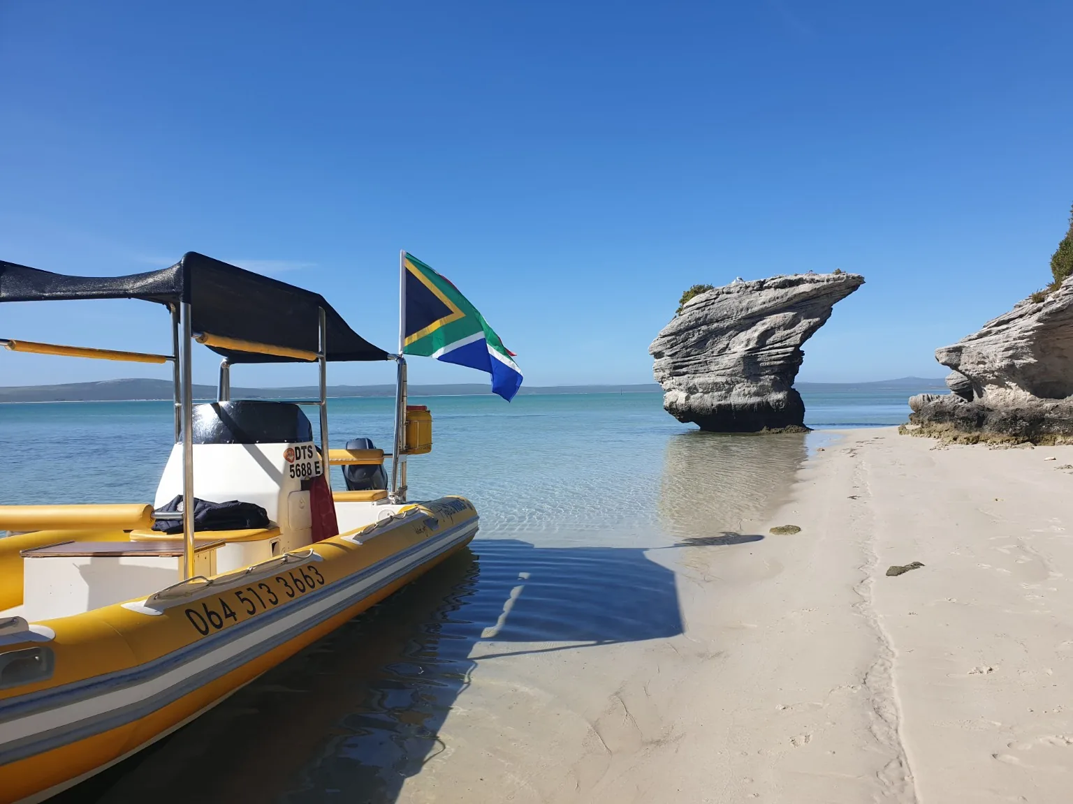 Aqua Vibes yellow boat beside a rock formation on Langebaan Lagoon